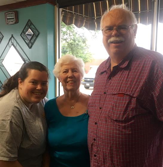 Three family members enjoy a joyful moment together in a diner during the daytime.
