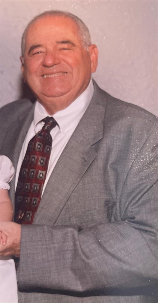 A smiling grandfather holds a baby at a joyful family gathering.