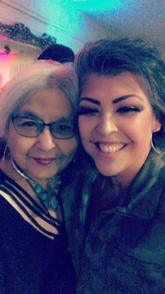 Two women share smiles and laughter at a lively event, showcasing their close relationship.