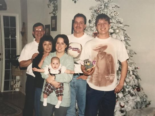 Family members smiling together, celebrating Christmas by a decorated tree.