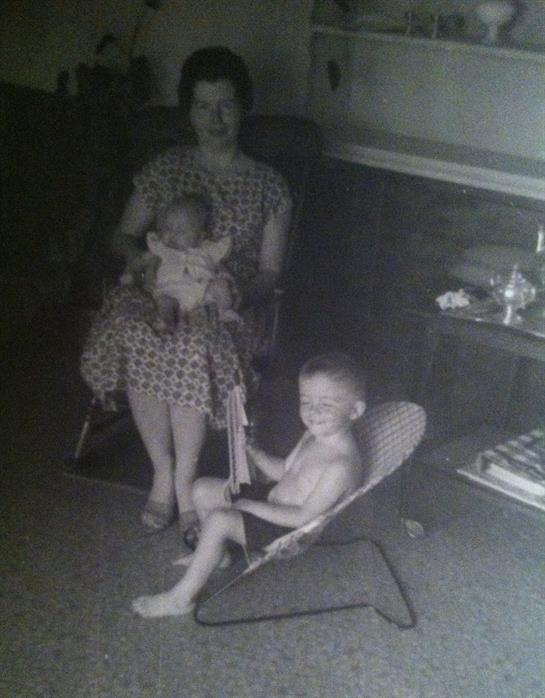 Children play joyfully while a woman watches them in a comfortable living room setting.