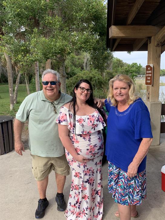Three friends enjoy a delightful gathering by the riverside, smiling and celebrating together.