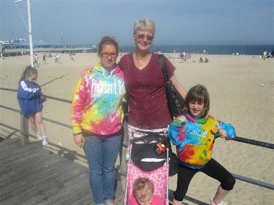 Three family members pose happily on the beach, showcasing their vibrant, tie-dye clothing.