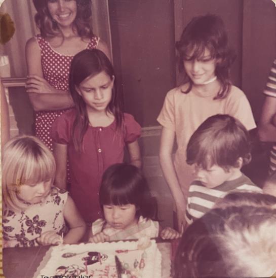 Children gather joyfully around a birthday cake, celebrating in a warm atmosphere.