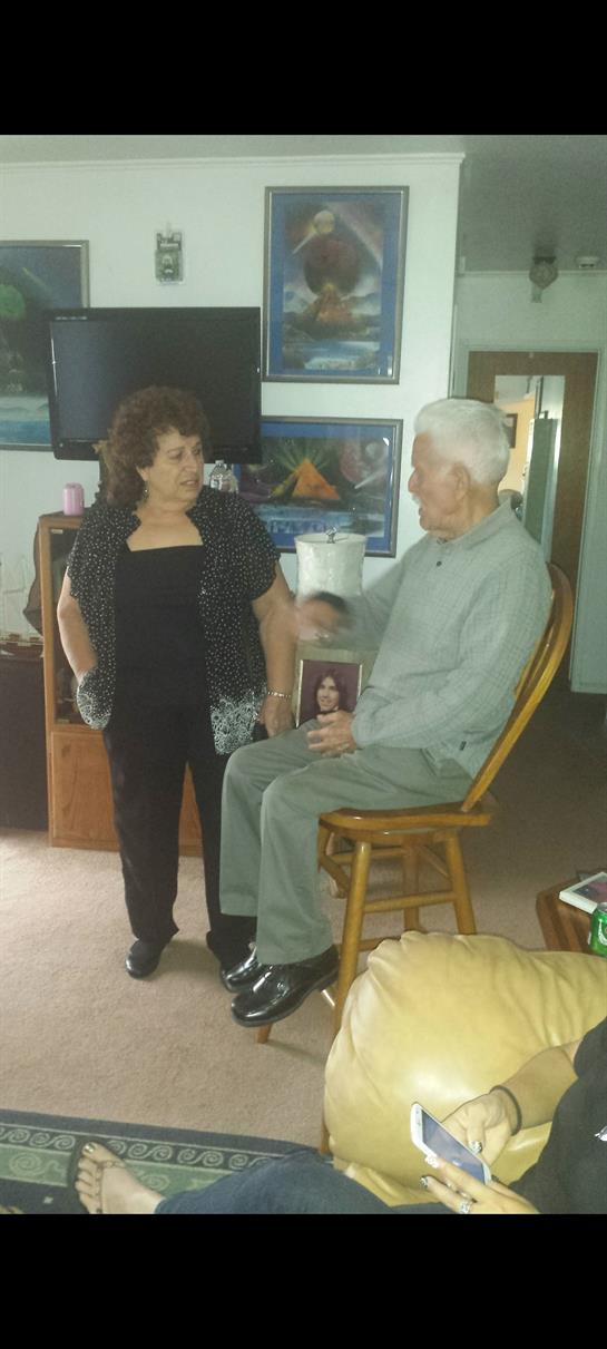 Two elders share a moment of connection and conversation inside a cozy living room.