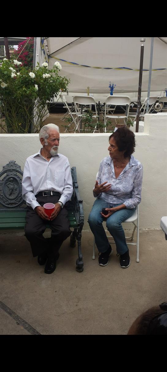 Two seniors share a joyful conversation while seated outdoors, surrounded by a relaxed atmosphere.