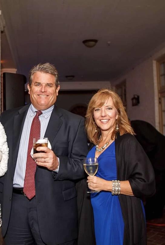 Friends in formal wear smile and enjoy drinks together at an event.