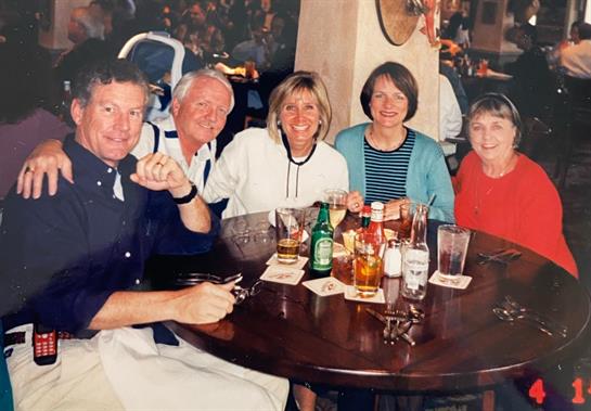 Friends are seated around a table, sharing food and drinks while enjoying each other's company.