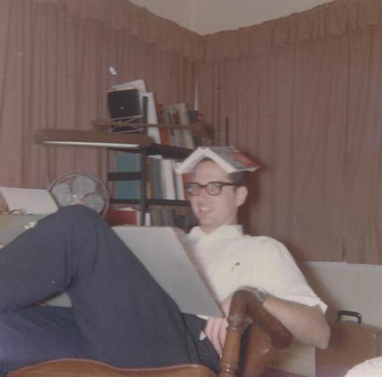 A young man relaxes in a comfortable chair, reading a book at home. Warm, inviting atmosphere.