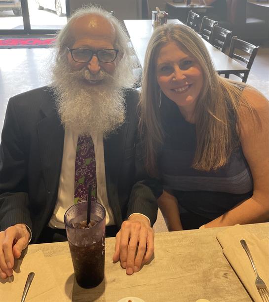 Two friends share a joyful moment at a restaurant, smiling while enjoying their drinks.