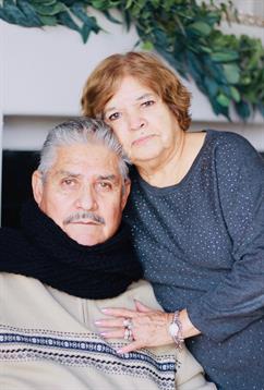 Elderly couple cozy in warm attire, sharing affection and closeness indoors.