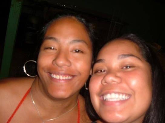 Two friends share a joyful moment together, smiling brightly in a lively social environment.