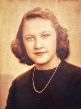 A woman poses for a classic portrait, showcasing her elegant hairstyle and necklace.