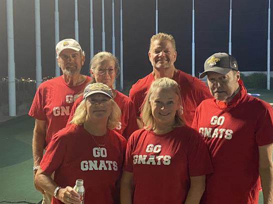 Cheerful group of friends proudly showing their support for their team in red shirts.