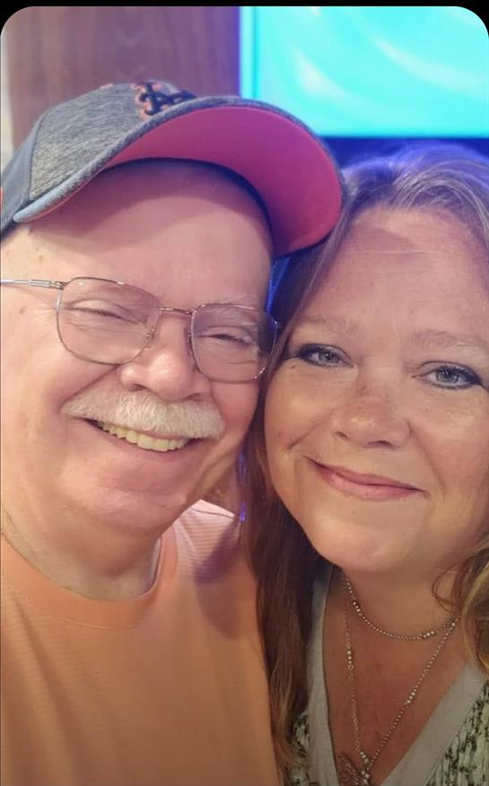Couple shares a joyful smile while celebrating at a lively summer event outdoors.