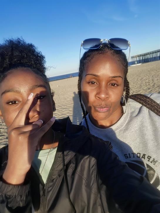 Friends taking a selfie at the beach on a sunny day, enjoying each other's company and the ocean.