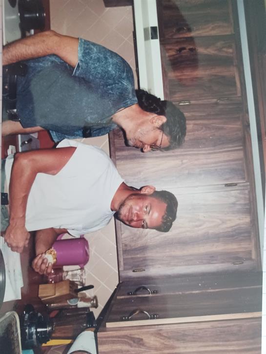 Two friends are engaged in cooking activities in a cozy kitchen environment, sharing a light moment.