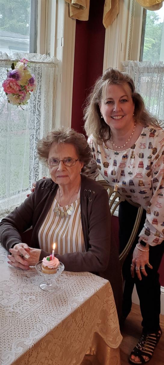 A woman sitting in a chair with a cake with a candle on it