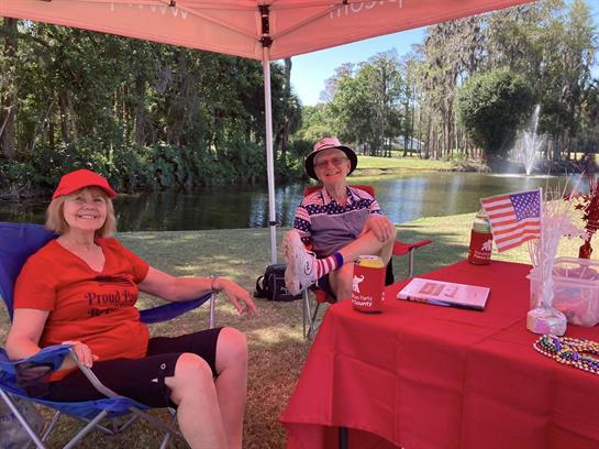 Two friends enjoy their time under a canopy near a peaceful pond on a warm afternoon.