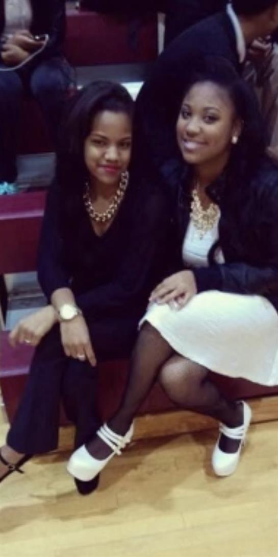 Two friends nearby showcase their stylish attire and joyful expressions during an event.