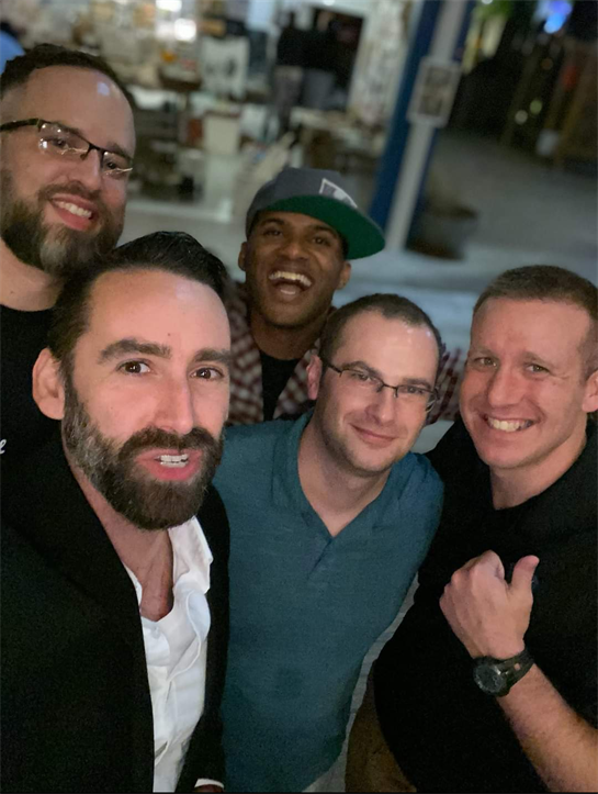 Friends smile and pose together at an urban location during a social evening gathering.