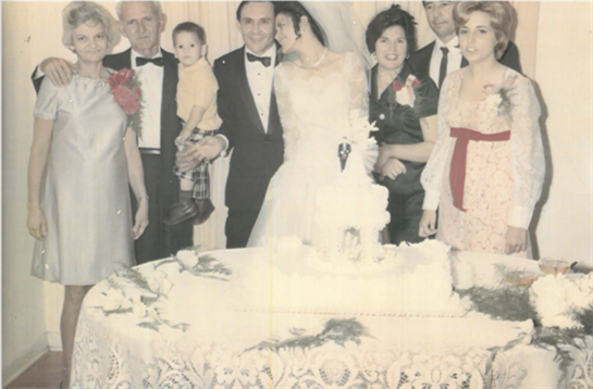 Guests gather around a beautifully decorated cake during a joyful wedding celebration event.