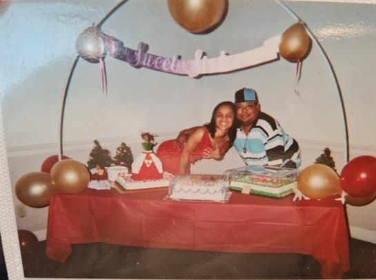 Two friends enjoy a festive atmosphere near a decorated cake and golden balloons.