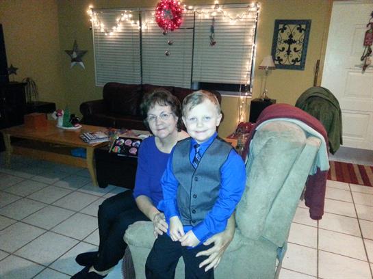 Adult and child dressed stylishly relax in a warmly lit living room adorned for celebration.