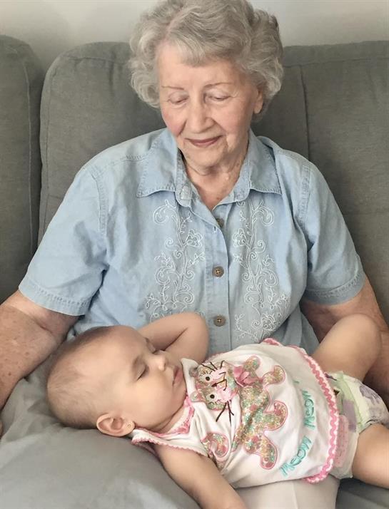 A loving grandmother enjoys a peaceful afternoon with her grandchild sleeping in her lap.