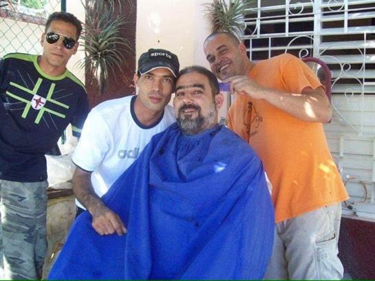 Friends gather around a man getting a haircut, capturing a moment of camaraderie and joy.