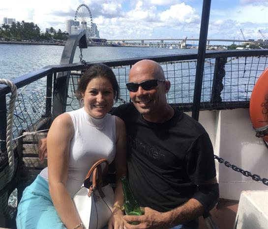 Smiling couple relaxes together on a boat, enjoying the sunny weather and beautiful surroundings.