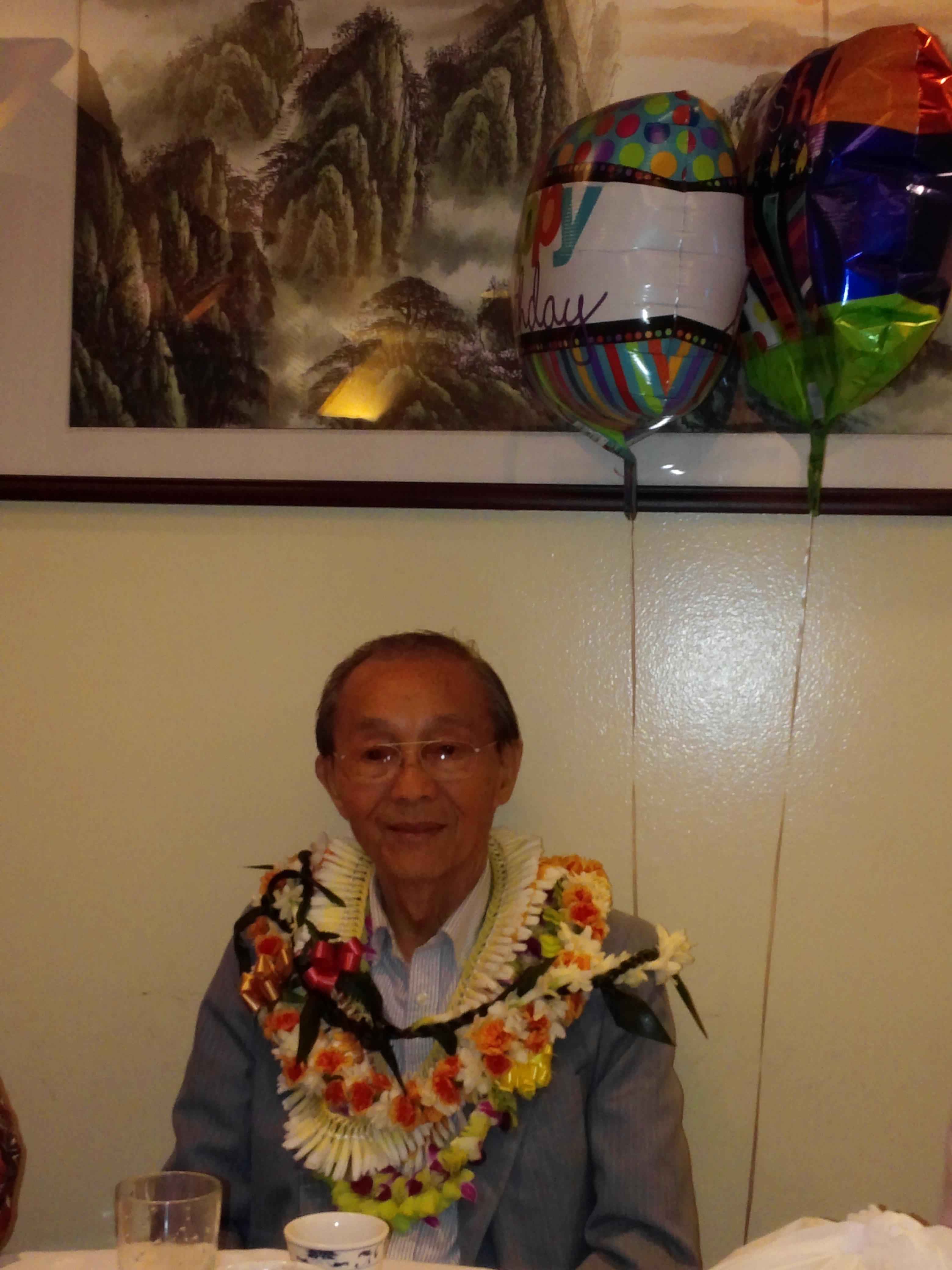 A man wearing a flower necklace and a balloon