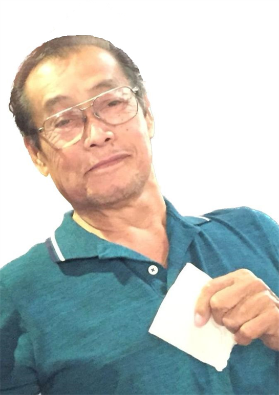 A cheerful elderly man is smiling and holding a small piece of paper in his hand.