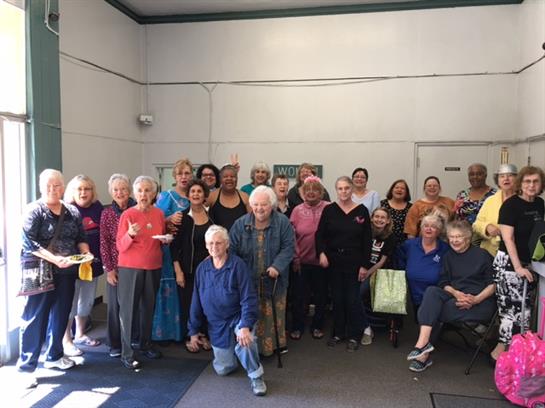 Seniors gather for a cheerful event in a spacious hall, smiling and socializing together.