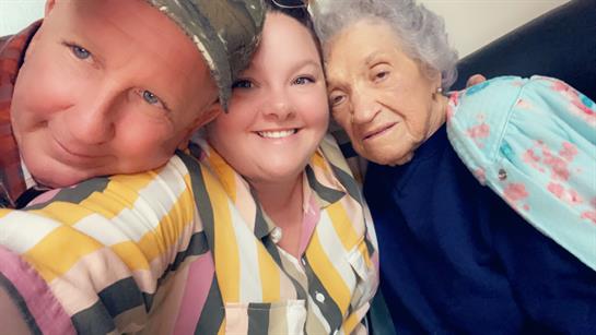 Two family members share a close moment with an elderly relative during a visit filled with smiles.