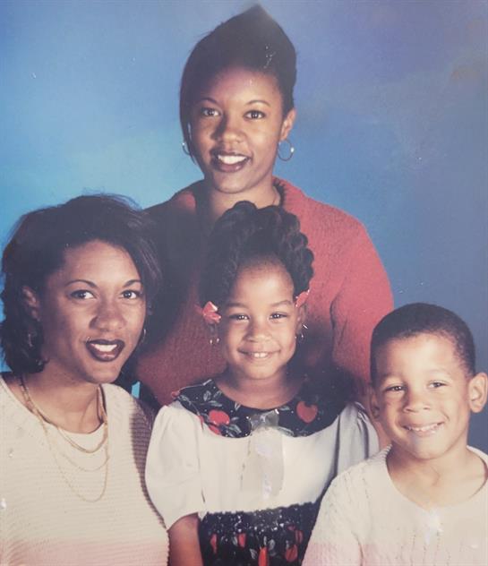 Four family members smile together, showcasing close bonds and happiness in a studio environment.