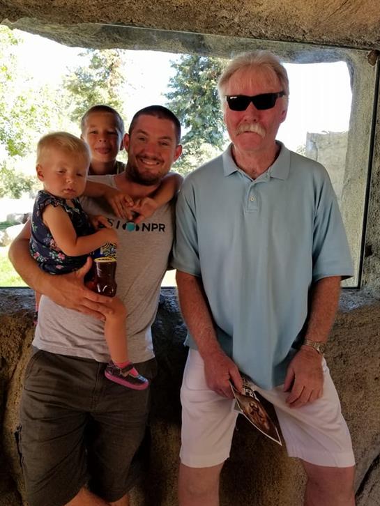 Group of friends and family members stand together inside a park shelter, smiling cheerfully.