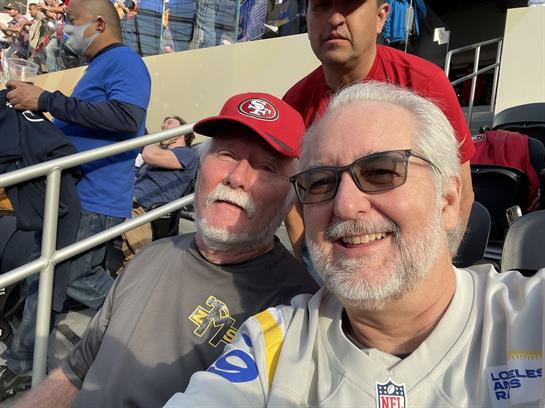 Two enthusiastic fans pose for a selfie while enjoying a thrilling football game.