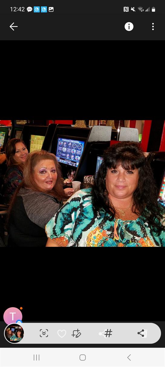 Four women interact while playing slots in a lively entertainment venue at night.