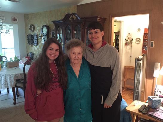 Three family members stand together in a warm living room, sharing a joyful moment.