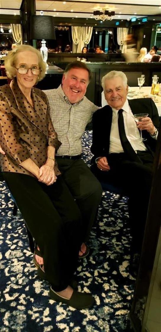 Three friends share smiles and conversation at a formal gathering in an elegant setting.