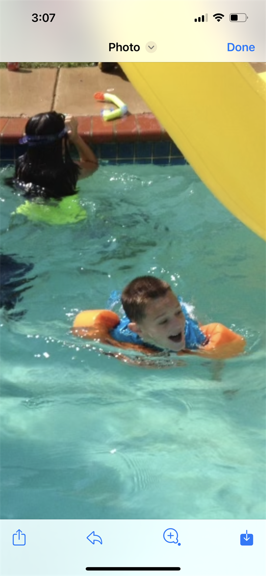 A boy in a pool with a floatie