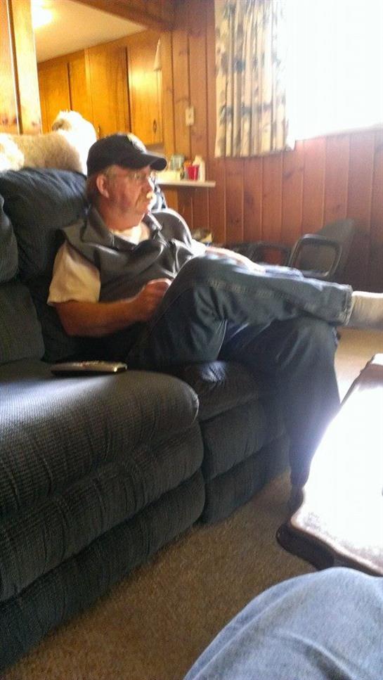 An older man relaxes on the couch, watching warm afternoon light through the window.