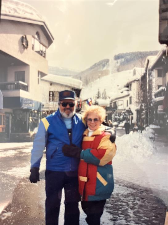 A happy couple in warm clothes enjoys the winter vibes in a snowy mountain village.
