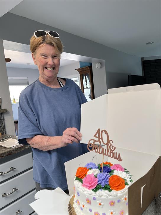 A woman joyfully holds a beautifully decorated cake for her 40th birthday celebration.