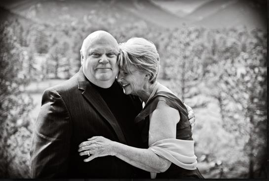 A couple shares an affectionate embrace in a beautiful mountainous setting, celebrating love.