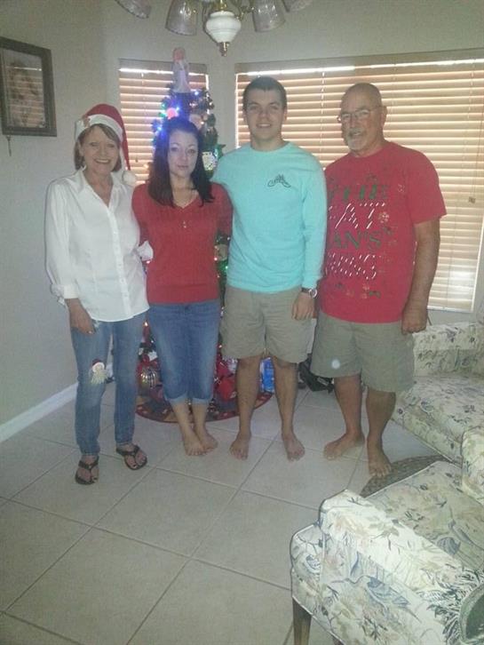 Four family members celebrate the holiday spirit by a cozy Christmas tree in the living room.