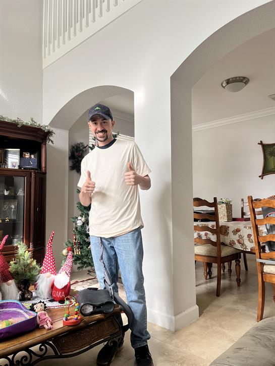 A cheerful man poses with thumbs up in a warm, inviting living room decorated for a gathering.