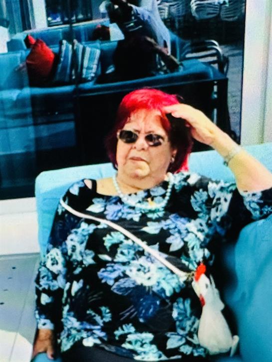 An older woman enjoys her time in a modern setting, wearing sunglasses and a floral outfit.