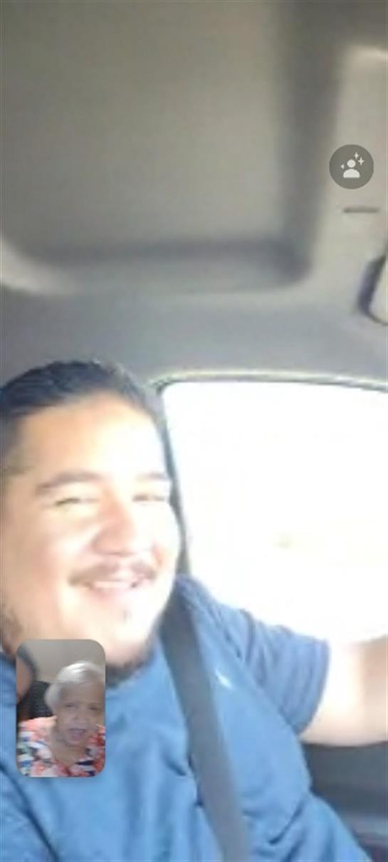 A man smiles brightly while driving, enjoying the warmth of a sunny day in the car.